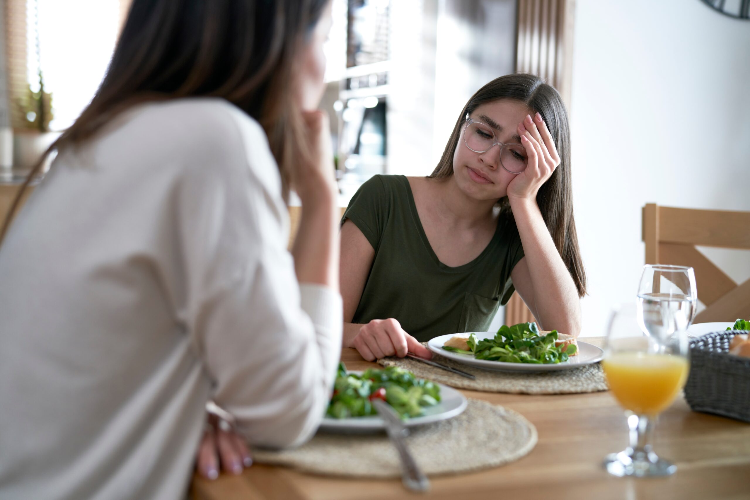 Mother supporting daughter with eating disorder during meal, highlighting the importance of family involvement in treatment.