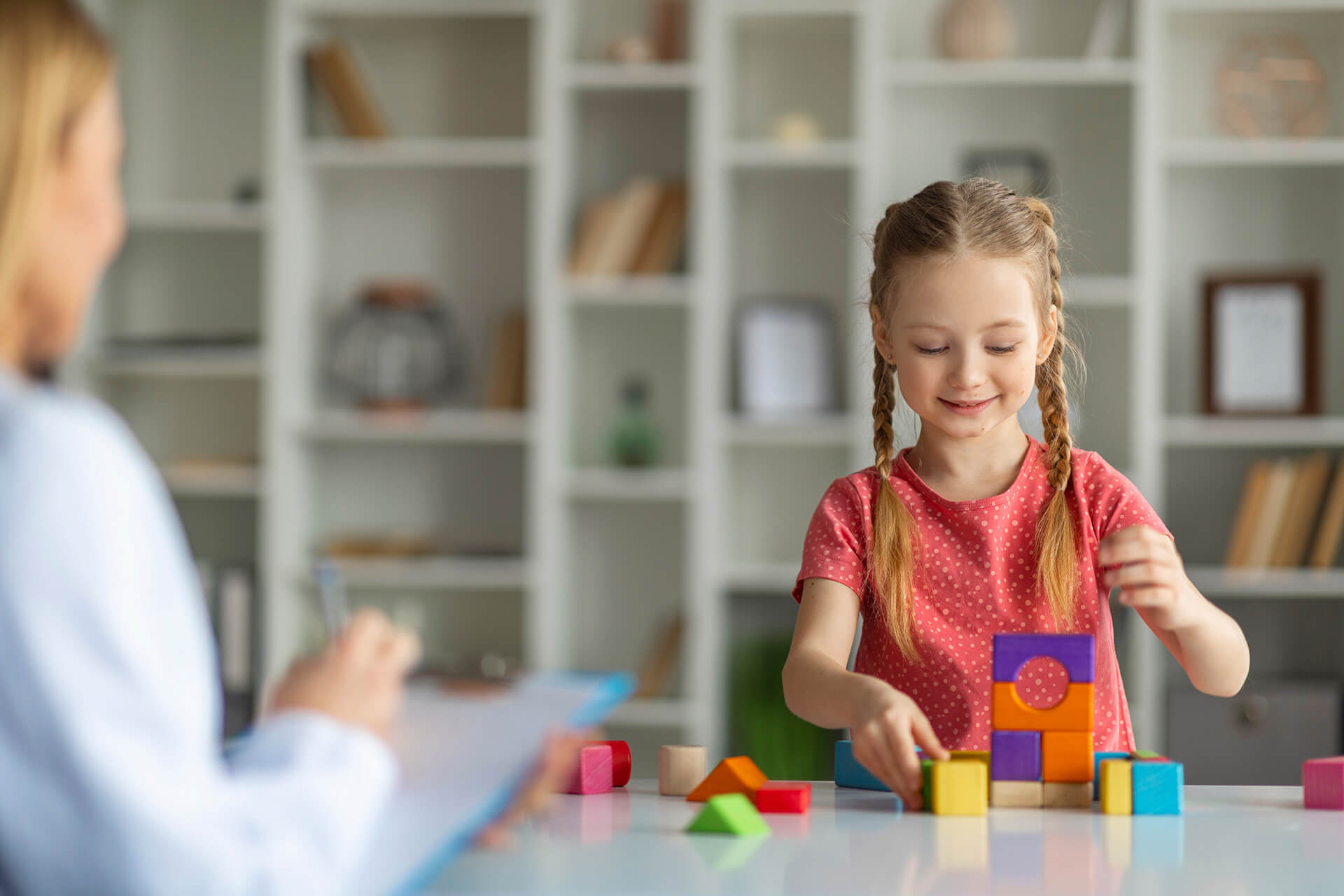 Young girl engrossed in building with puzzle blocks, using play therapy as a tool for development or treatment of eating disorders such as anorexia, bulimia, and binge eating