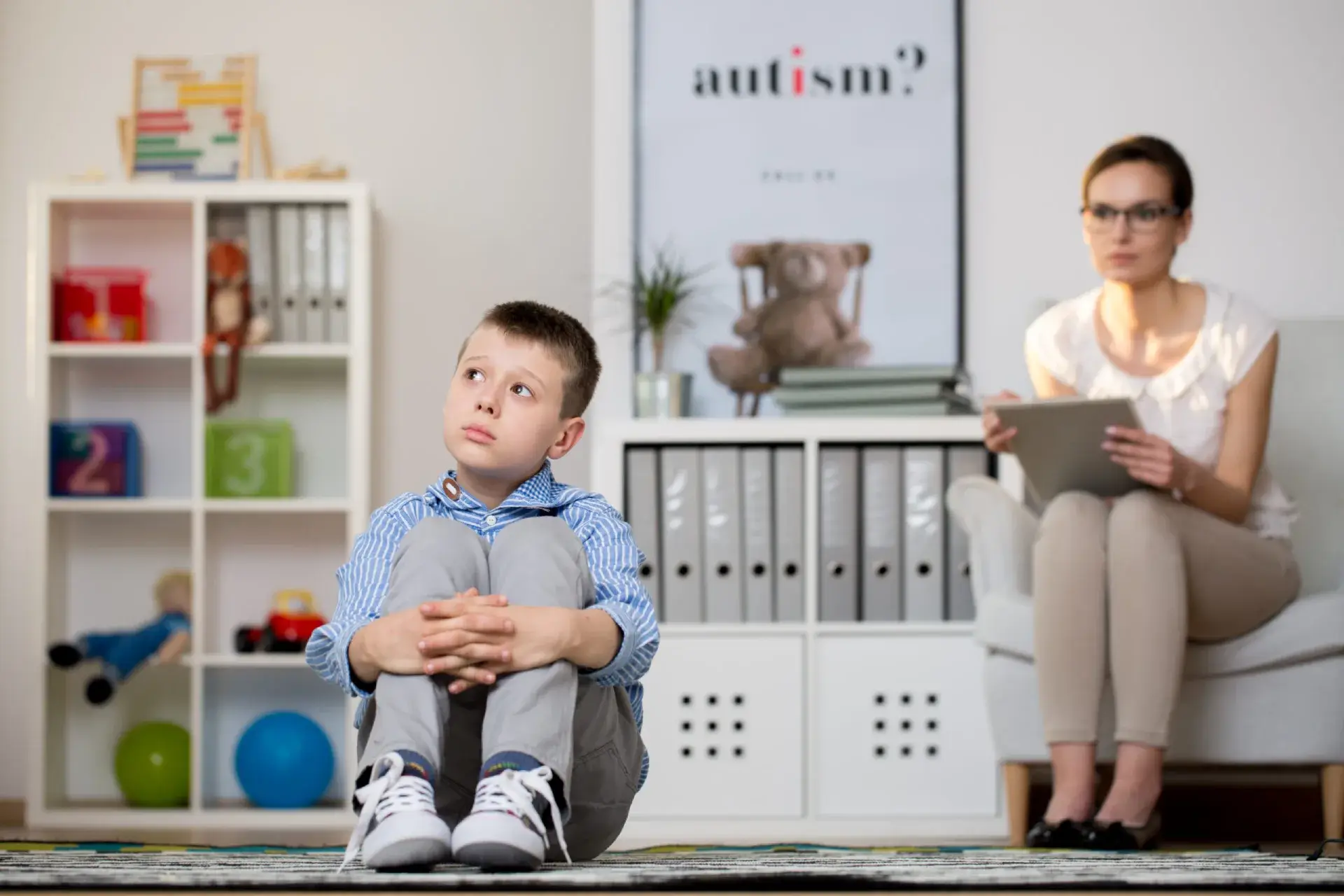 Psychologist observing a young boy with autism during a therapy session